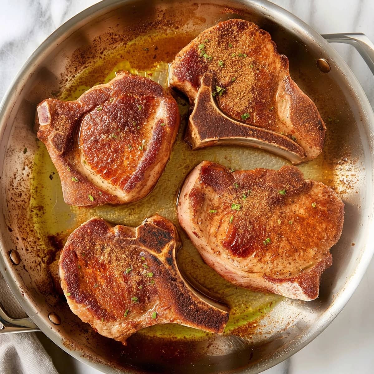 Pork chop with dry rub seasoning seared in a skillet.