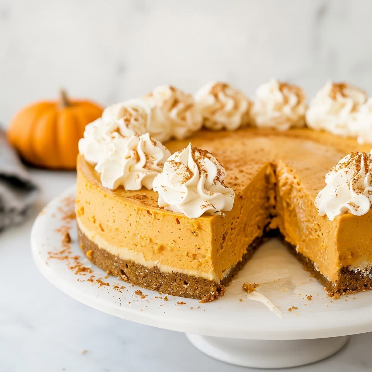 Heavenly no-bake pumpkin cheesecake topped with whipped cream, a festive treat perfect for Thanksgiving or any autumn celebration