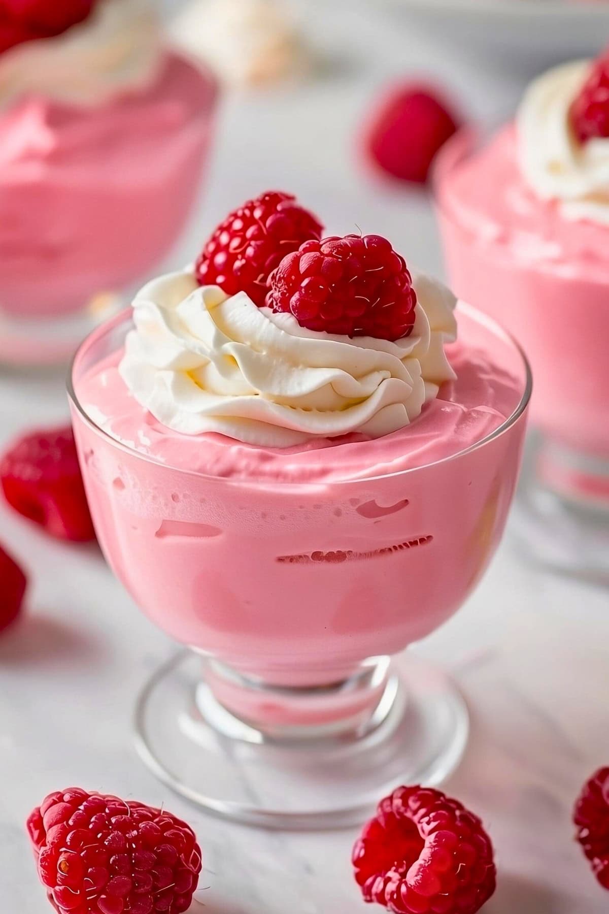 Raspberry mousse with whipped cream and raspberries on top.