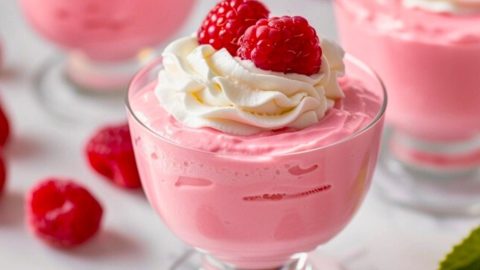 Raspberry mousse with whipped cream and raspberry garnish on top.