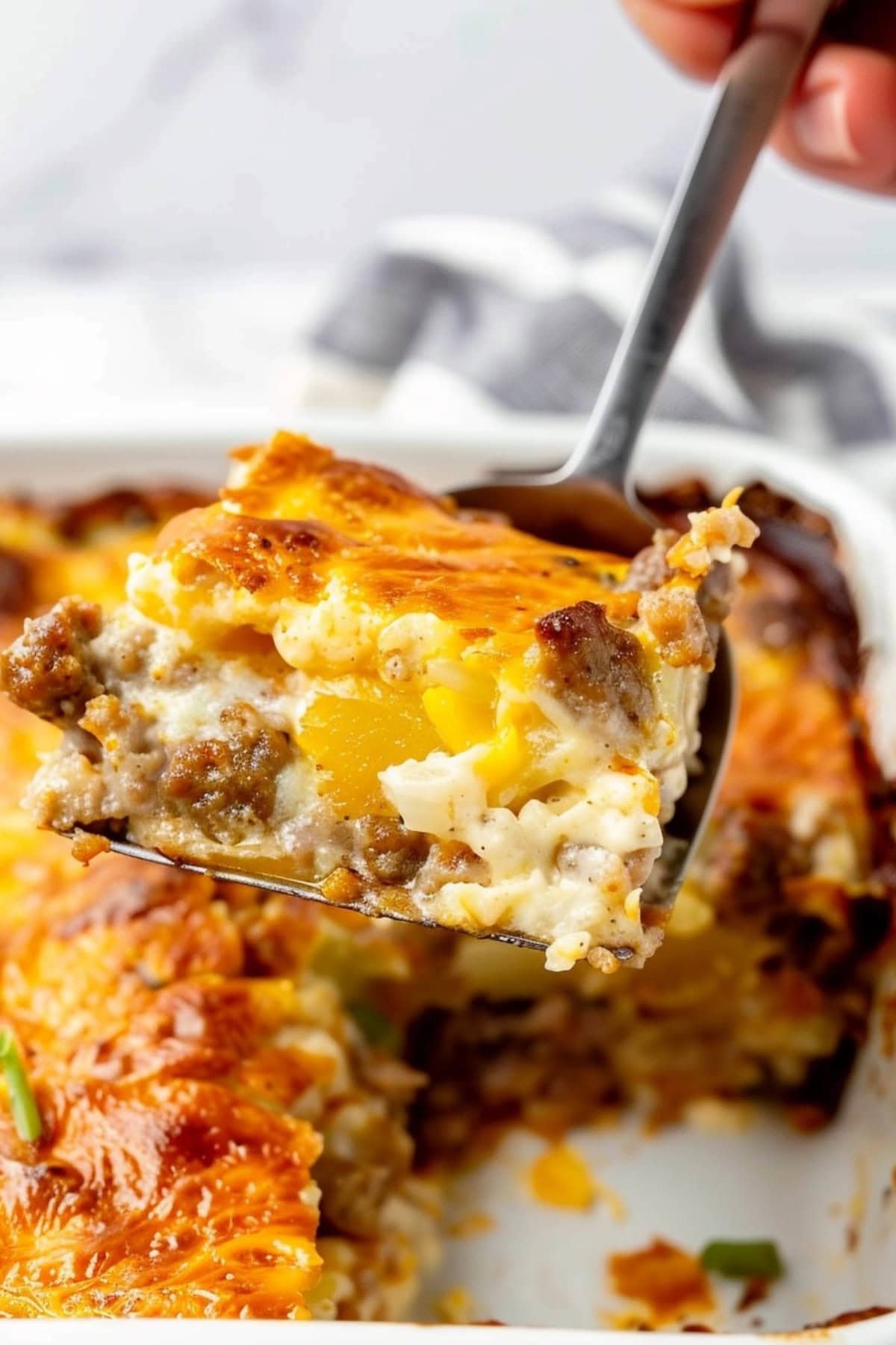 Slice of Sausage hashbrown breakfast casserole in lifted by pie ladle.