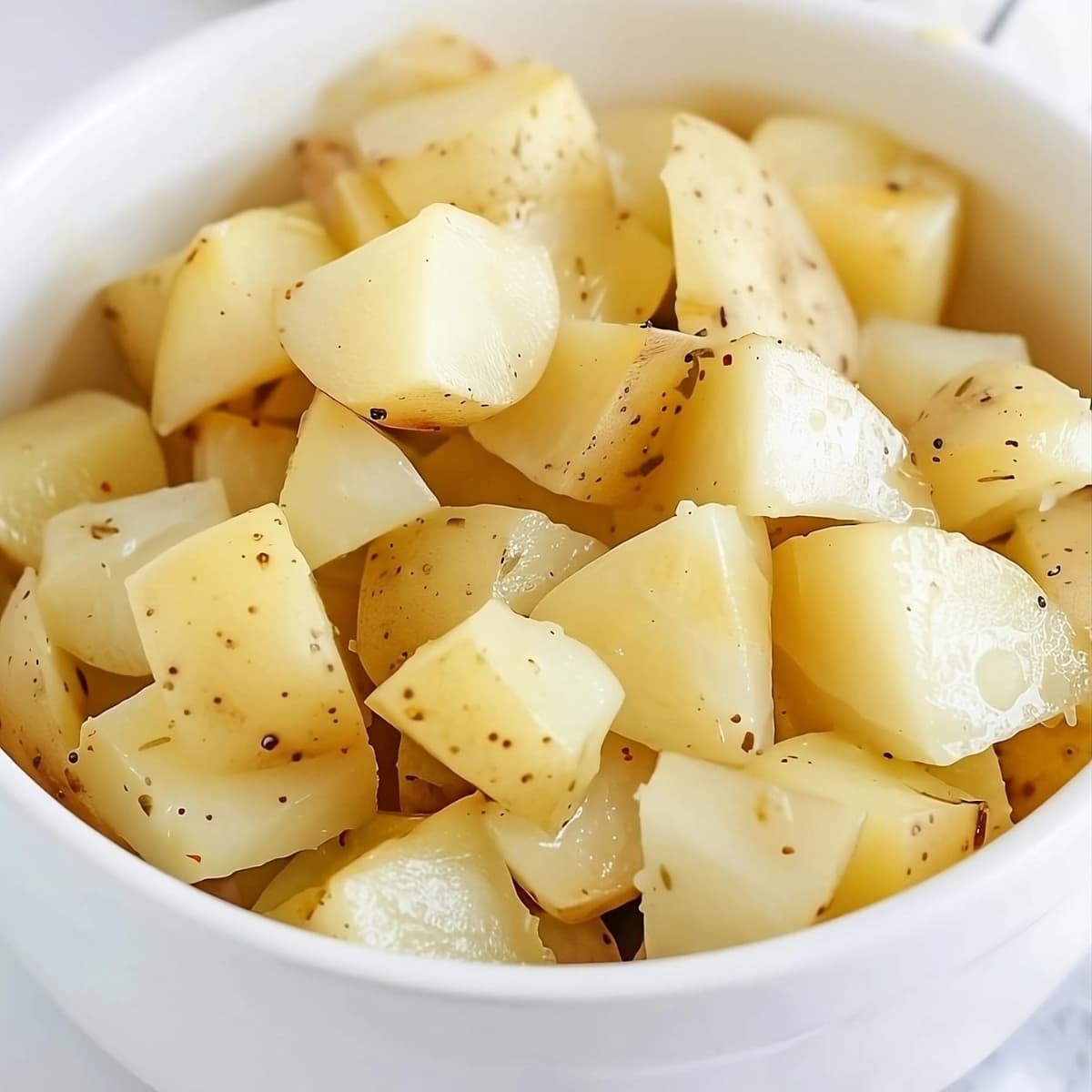 Baked potatoes sliced in cubes served in a white bowl.