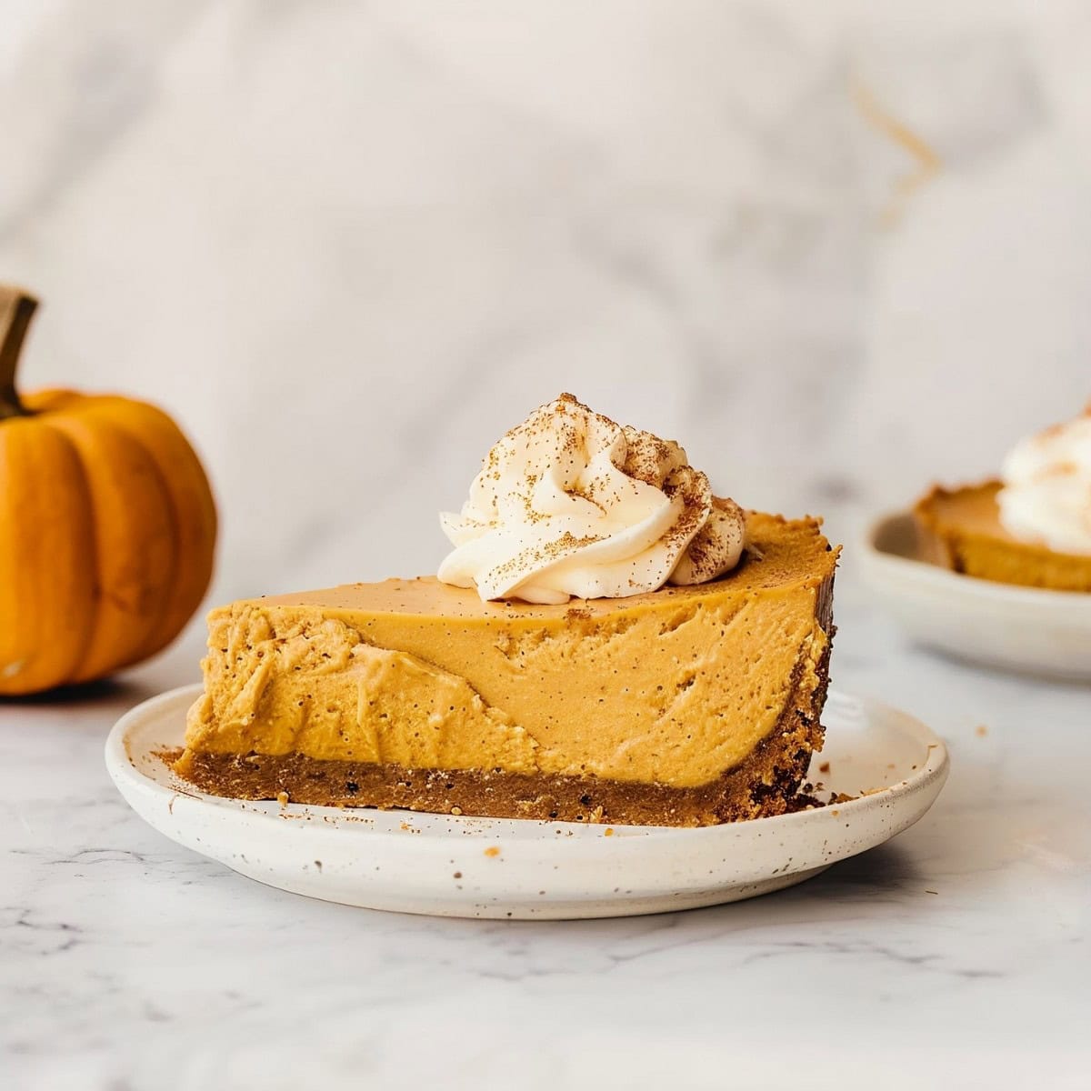 Irresistible no-bake pumpkin cheesecake, topped with a dollop of whipped cream and a sprinkle of cinnamon