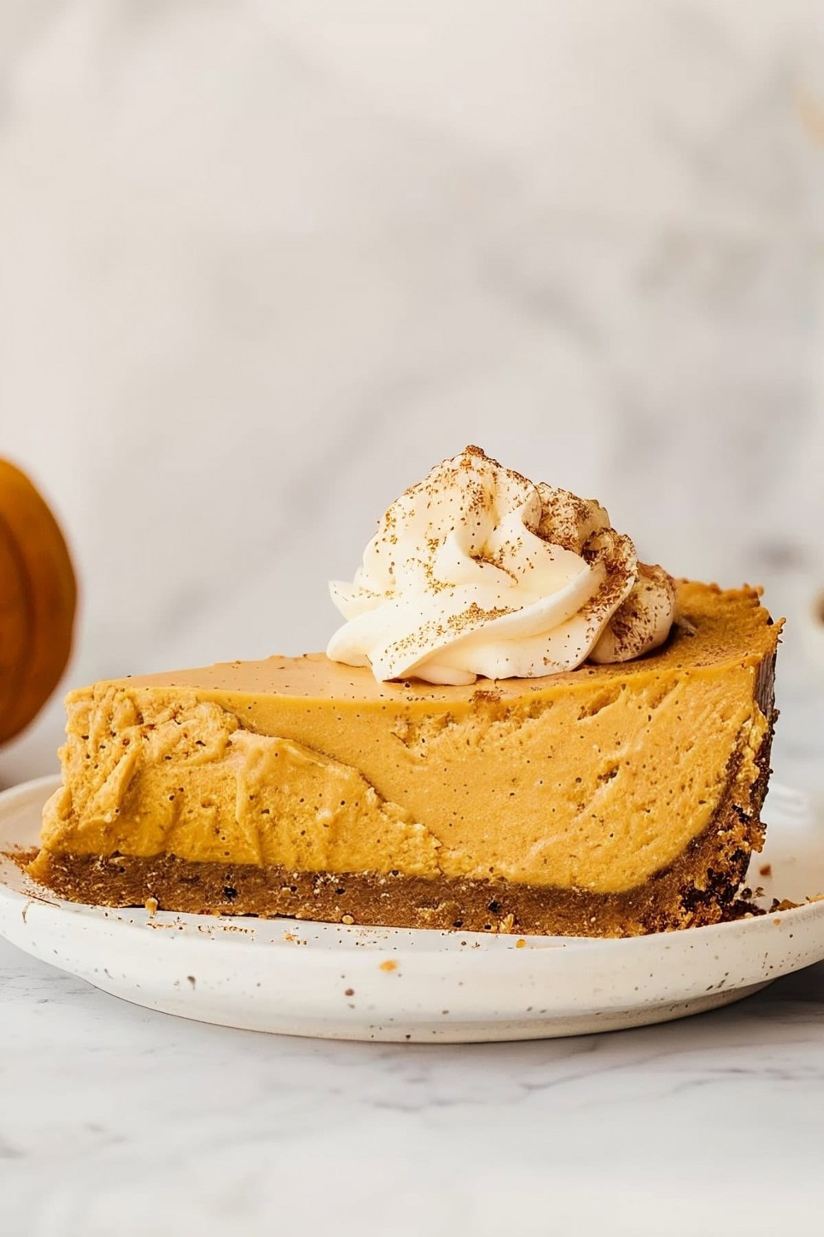 Homemade no-bake pumpkin cheesecake, topped with a swirl of whipped cream and a sprinkle of cinnamon for extra flavor