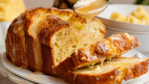 Sliced pineapple quick bread with spoonful of sugar glaze dripping over it.