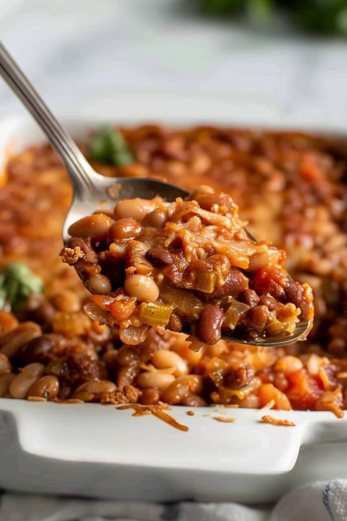 Spoonful of three bean casserole from baking dish.