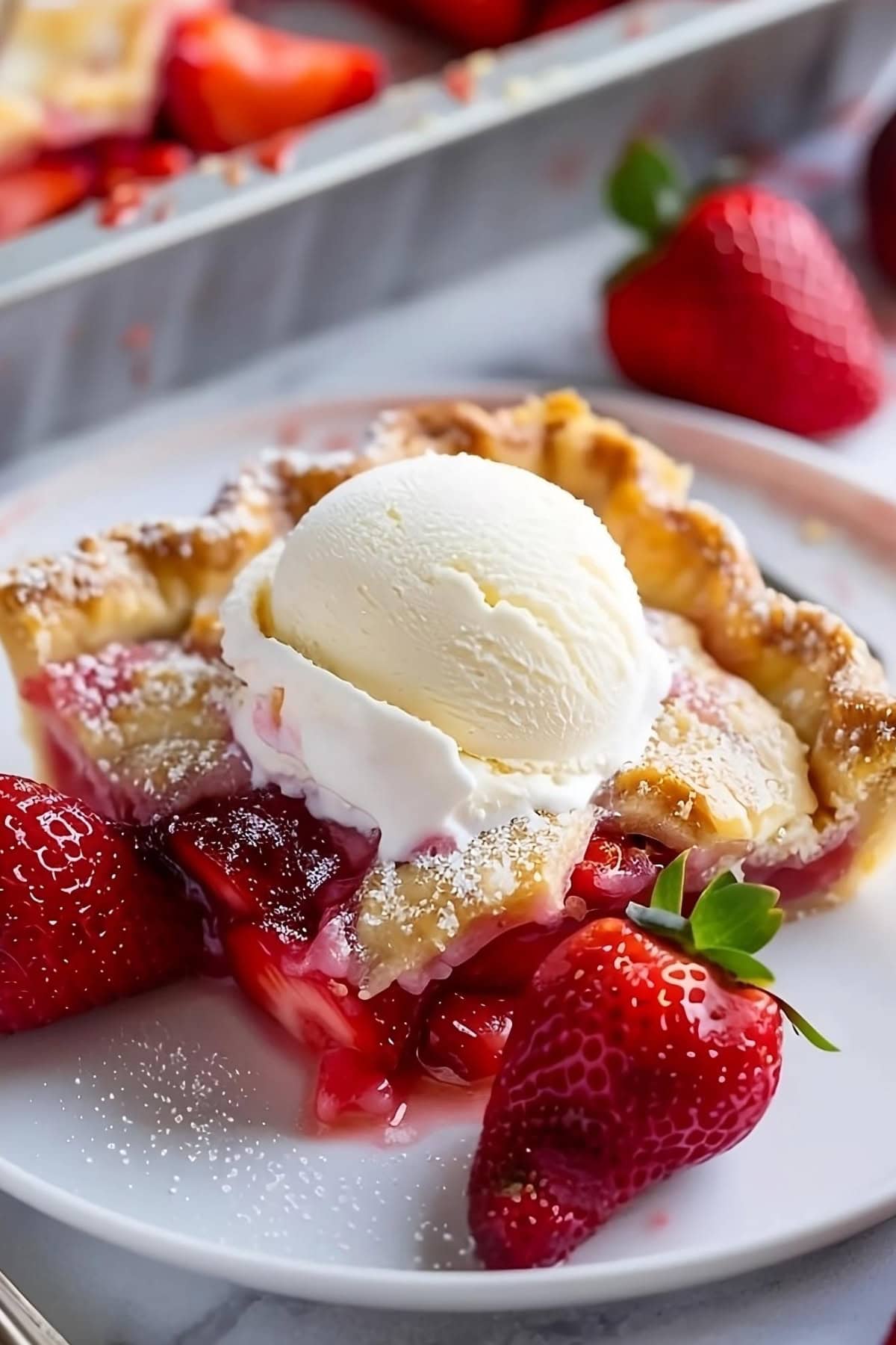 Square slice of strawberry slab pie on a plate with scoop of vanilla ice cream and fresh strawberries.