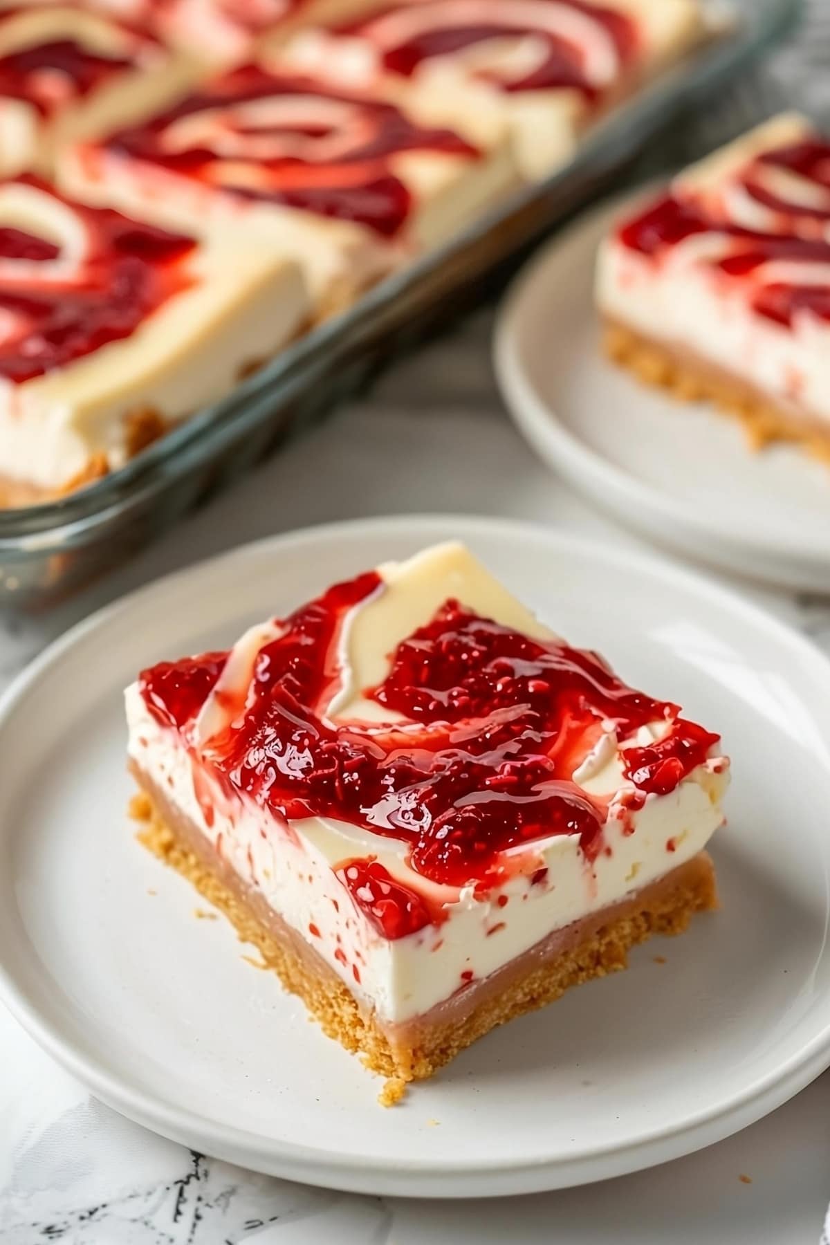 Sliced strawberry cheesecake bar on a plate.