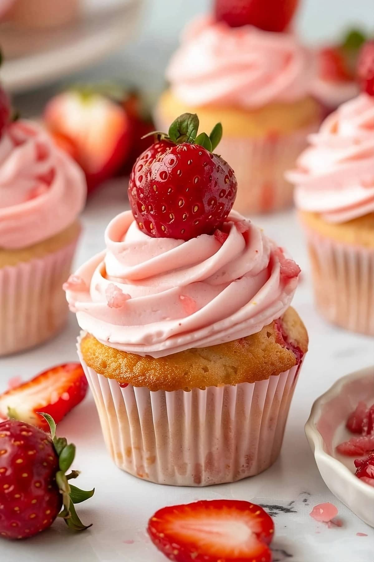 Strawberry cupcake with frosting and fresh strawberry garnish.