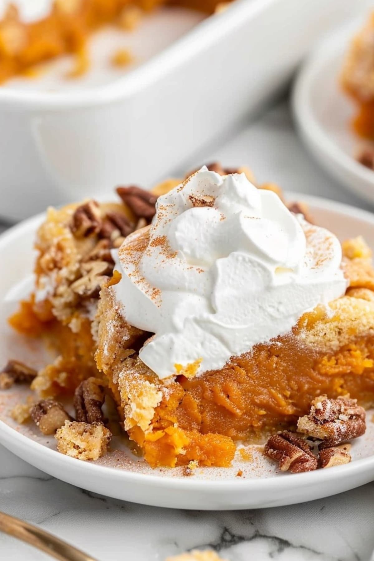 Slice of sweet potato dump cake with whipped cream on top served on a white plate.