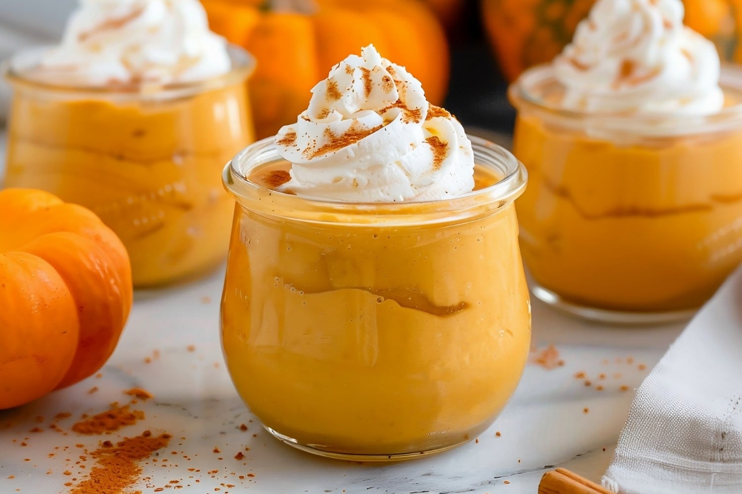 Three pumpkin mousse in jars with pumpkin spice and whipped cream