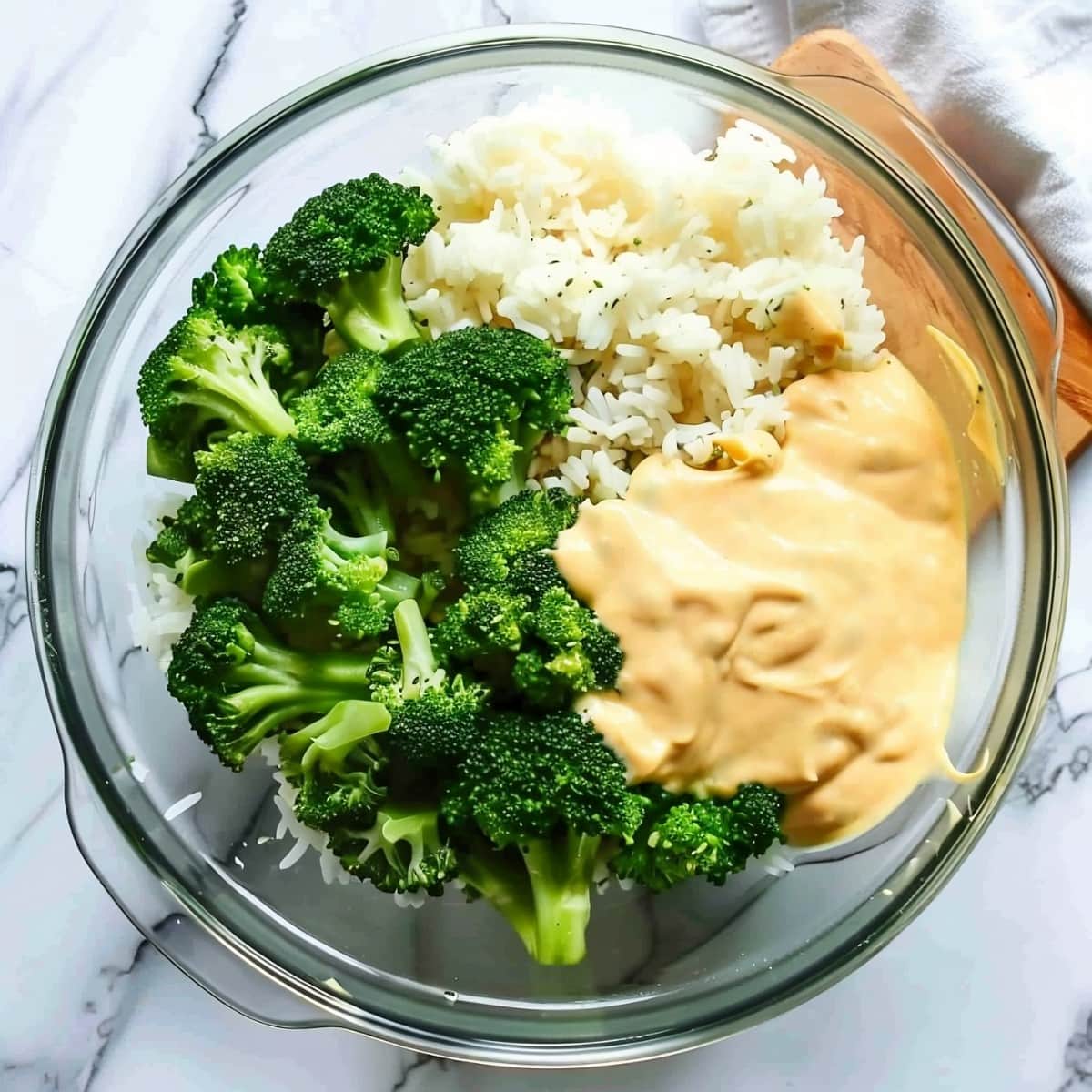 A large glass bowl of fresh broccoli, rice and cheese sauce