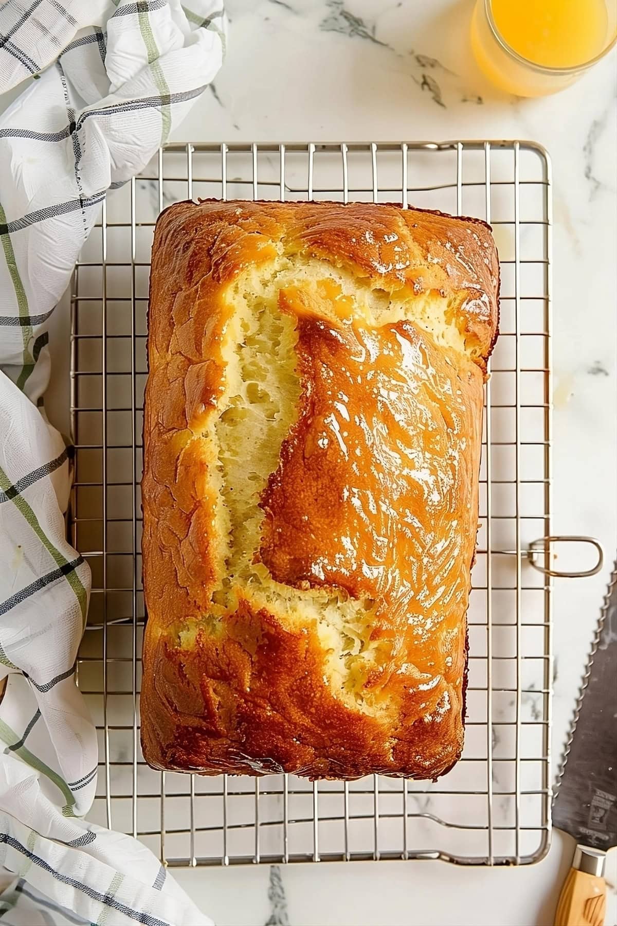 Top view of pineapple loaf bread on a cooling rack on a white marble table.