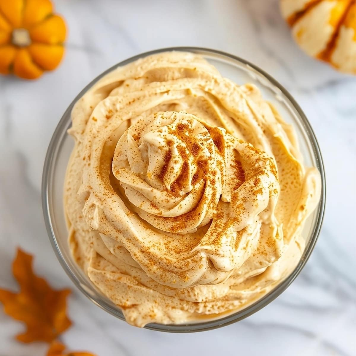 Top view of pumpkin whipped cream sprinkled with pumpkin spice served in a glass bowl.