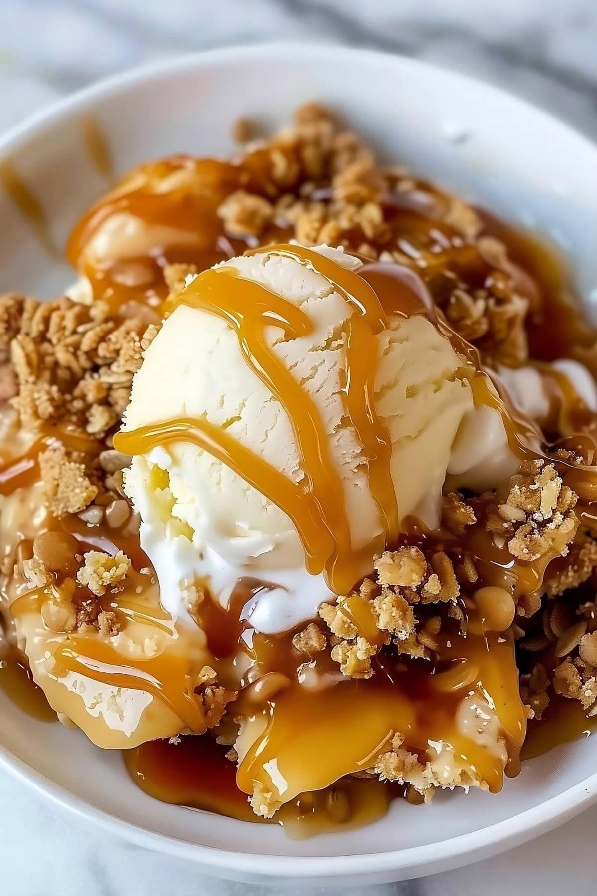 Close up of Caramel Apple Crisp in a bowl with a scoop of ice cream