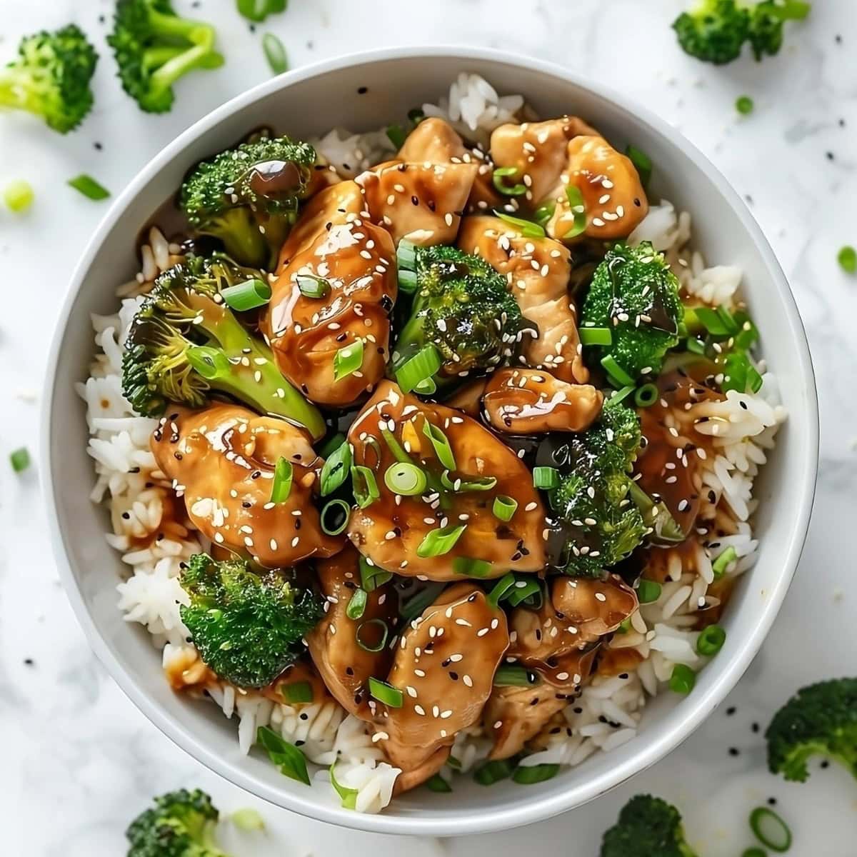 Top view of a bowl of rice with stir fried chicken and broccoli on top.
