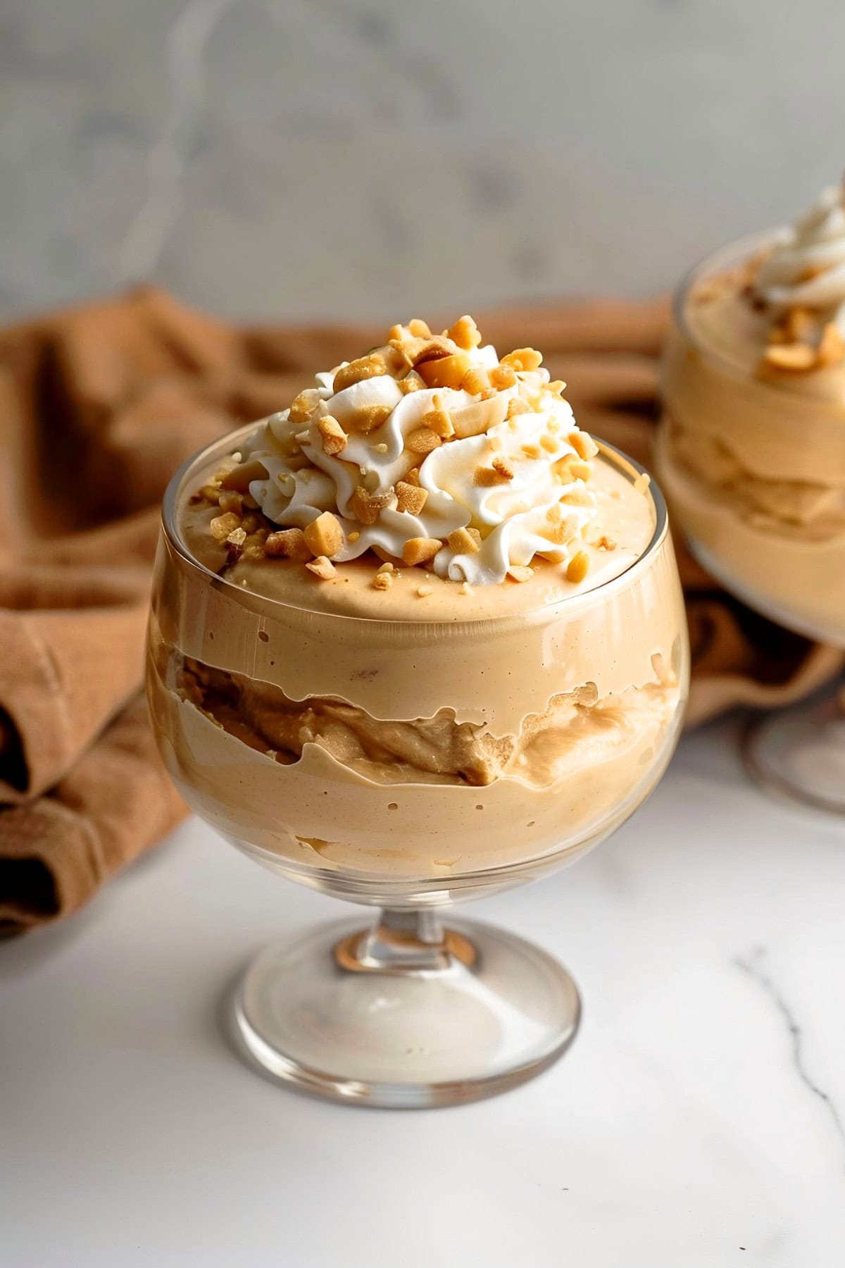 Creamy peanut butter mousse topped with whipped cream and chopped nuts