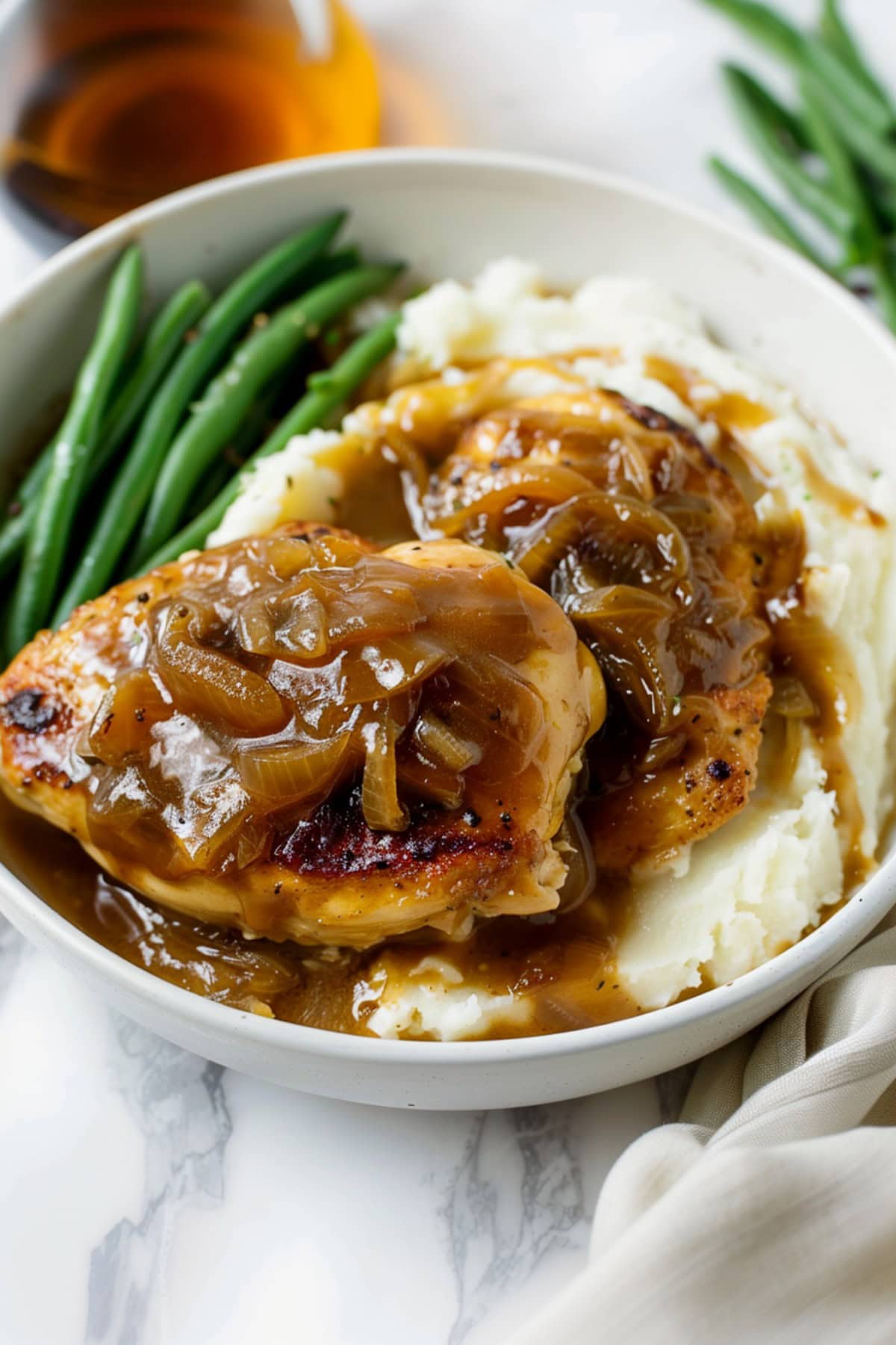 A bowl of French onion chicken with green beans and mashed potatoes