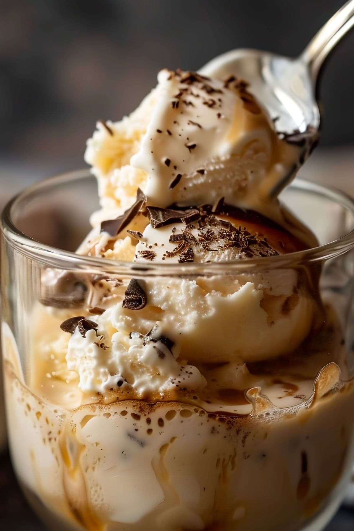 Affogato with Vanilla Ice Cream, Amaretto, and Espresso with Chocolate Shavings in a Glass with a Spoon Taking a Bite