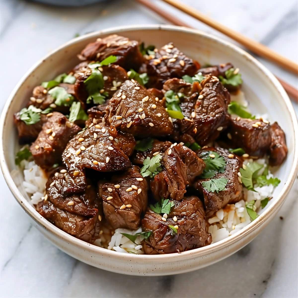 Tender chunks of Asian steak bites served with rice in a bowl