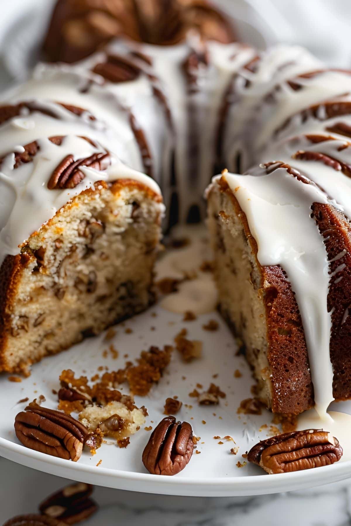 Close Up of Bacardi Rum Cake with Rum Glaze and Pecans, with a Slice Removed on a White Cake Stand
