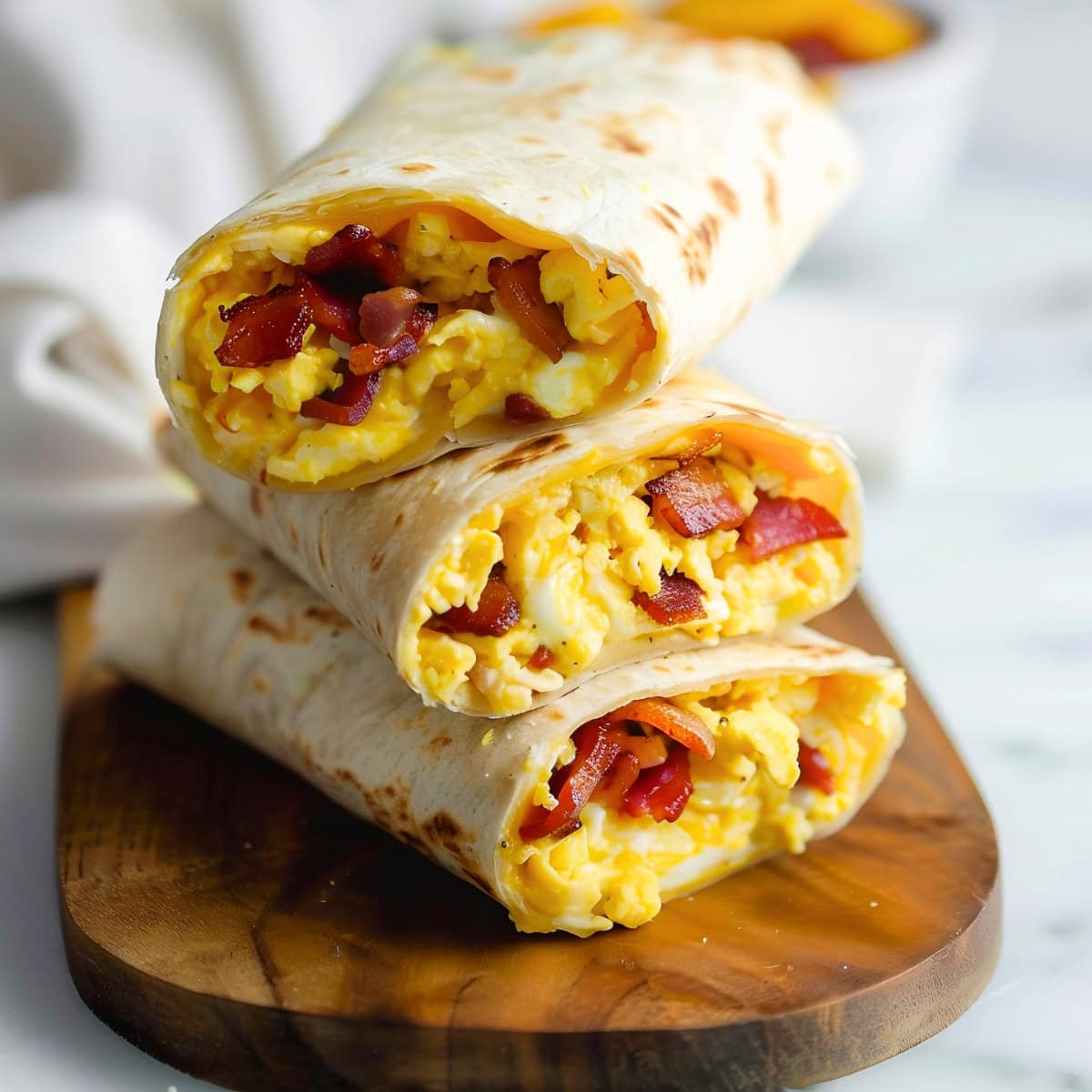 A breakfast wrap with bacon, egg and cheese on a wooden board.