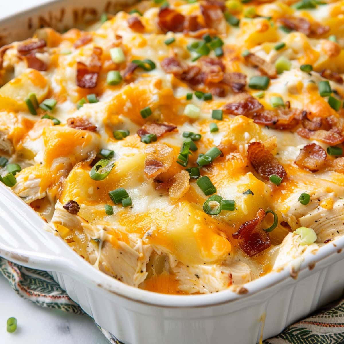 Close up view of baked cheesy chicken and potato casserole.