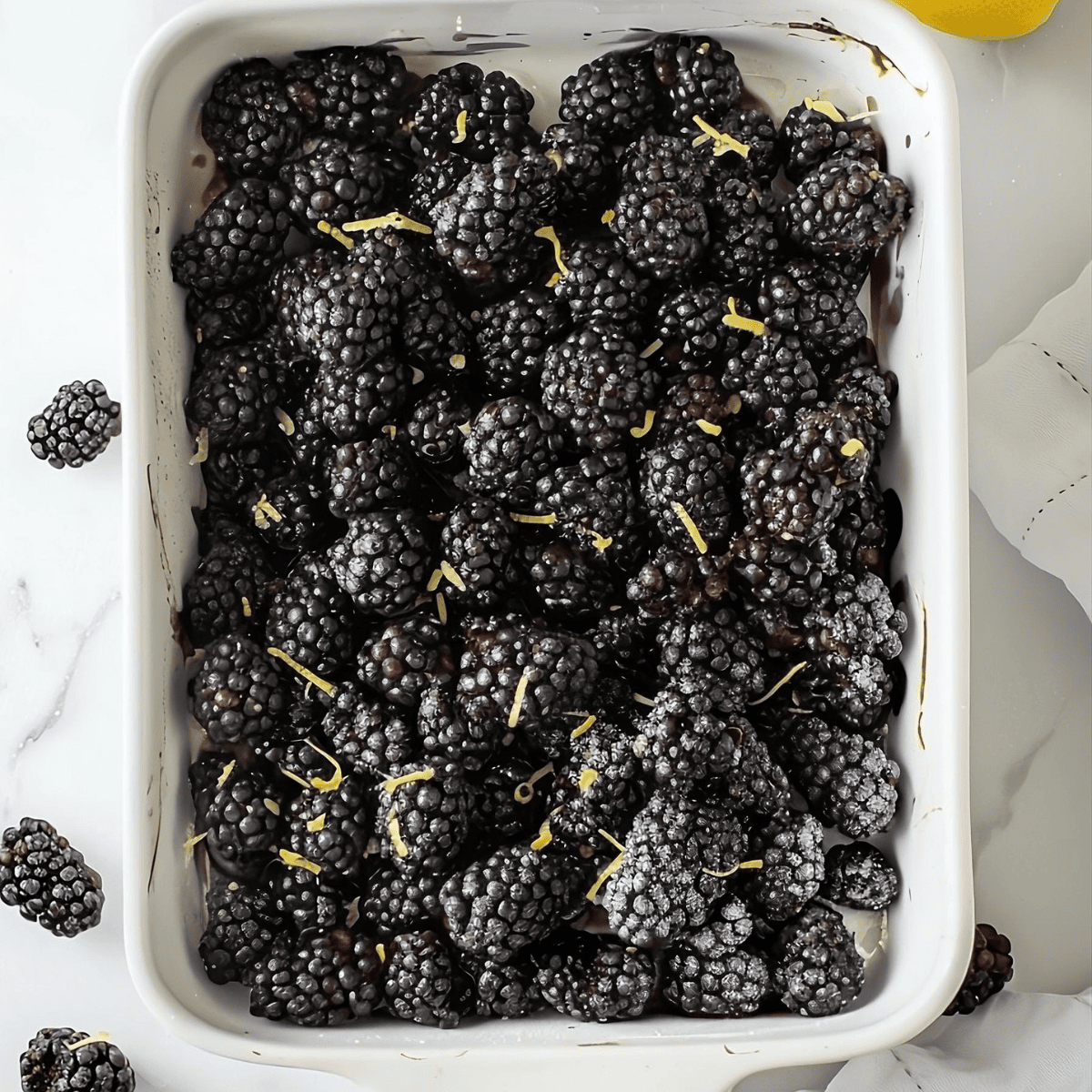 Blackberries with lemon zest in baking dish.