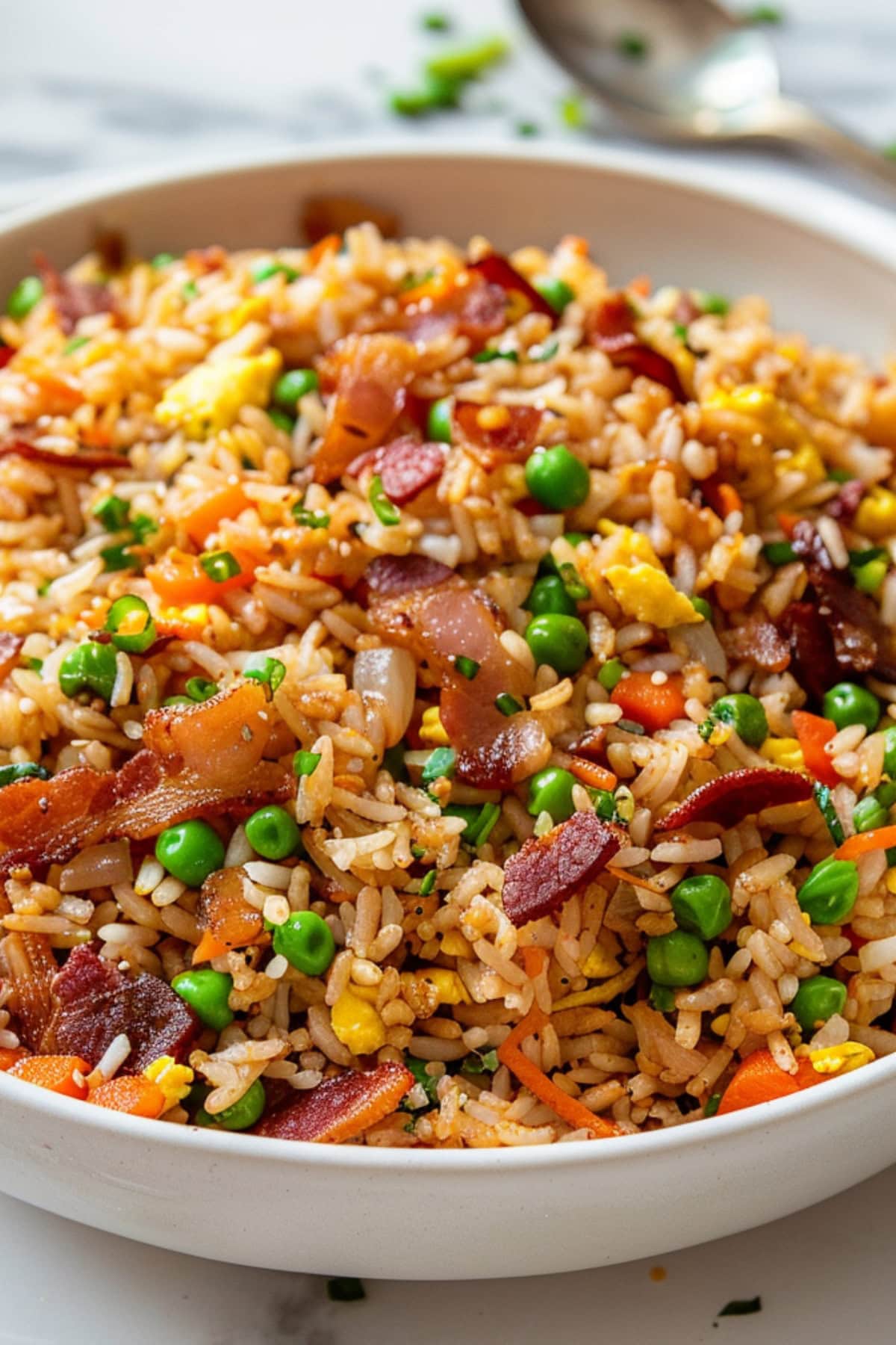 Fried rice mixed with bacon, green peas, carrots, egg and soy sauce