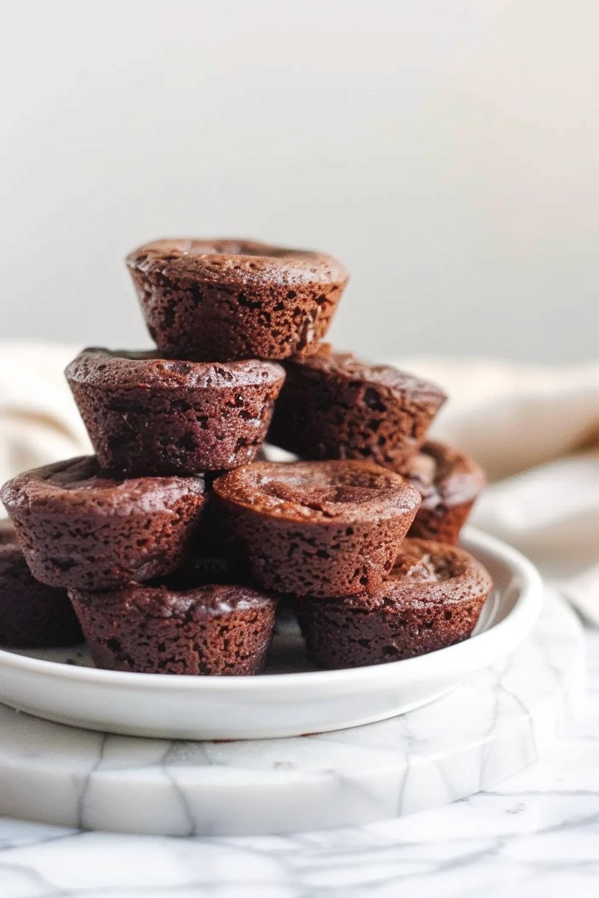 A stack of brownie bites on a white plate, showcasing their moist and chewy texture