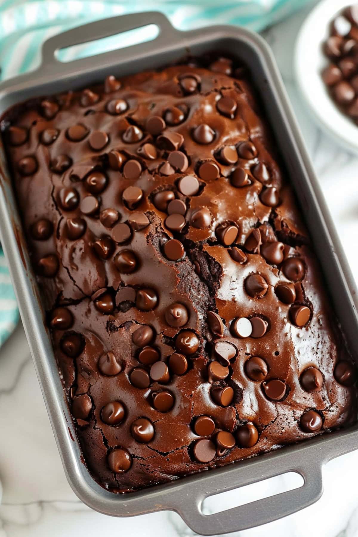 Overhead view of brownie bread in a loaf pan on a white marble table