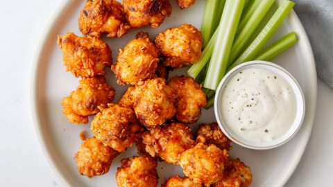 Appetizing spicy buffalo chicken bites served with celery sticks and ranch dressing dip