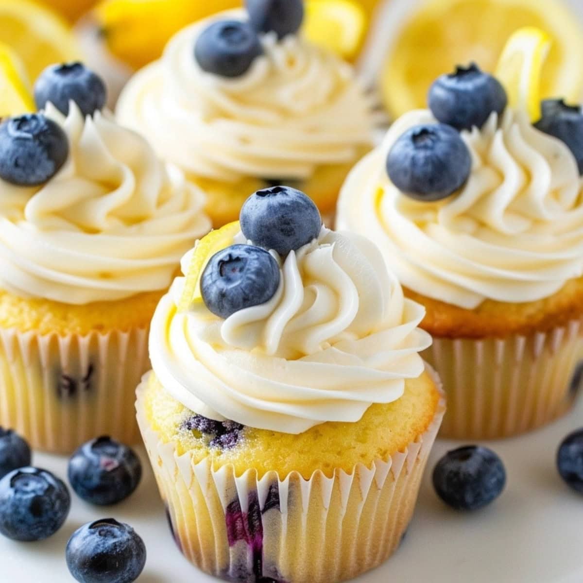 Bunch of lemon blueberry cupcakes with creamy frosting garnished with berries and lemon zest.