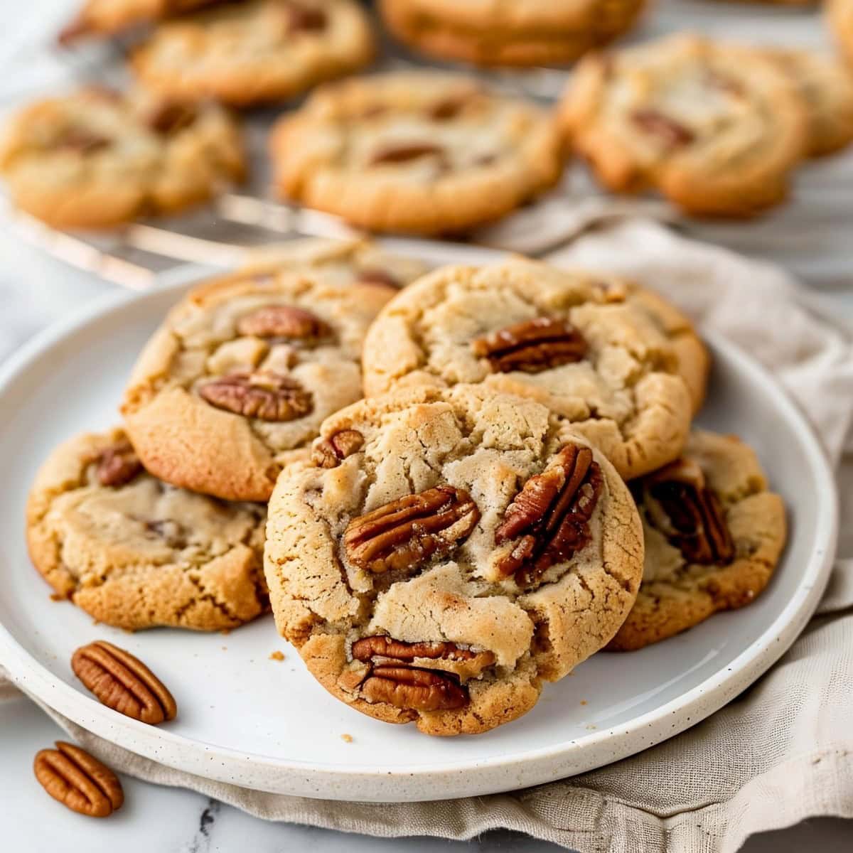 Nutty homemade butter pecan cookies in a white plate, kitchen towel on the side