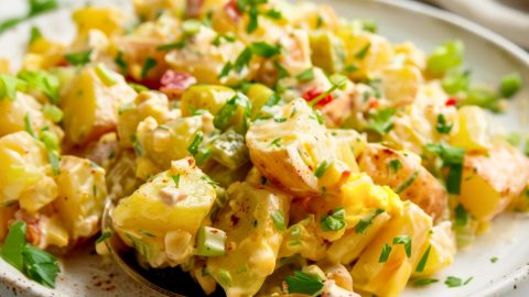 Serving of potato cajun salad in a plate with spoon.