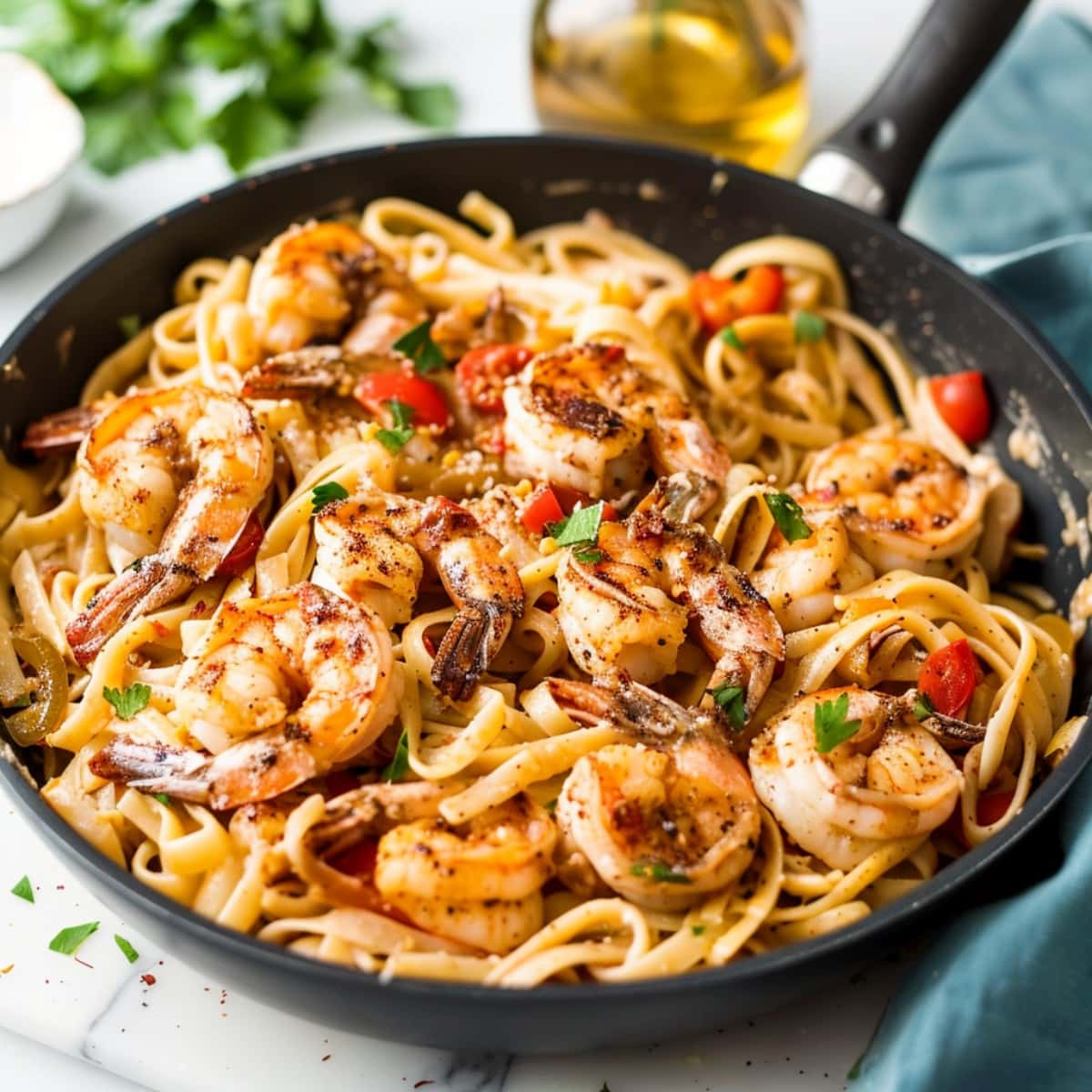 A black skillet filled with Cajun shrimp pasta infused with salt and pepper, garnished with fresh parsley