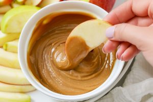 A bowl of rich, creamy caramel dip surrounded by fresh apple slices
