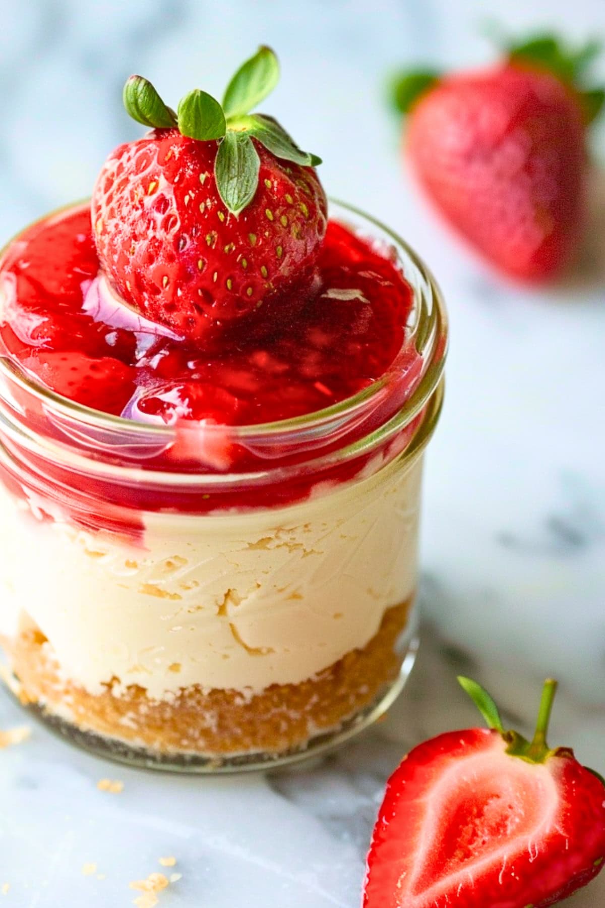 Jar of cheesecake with strawberry on top.