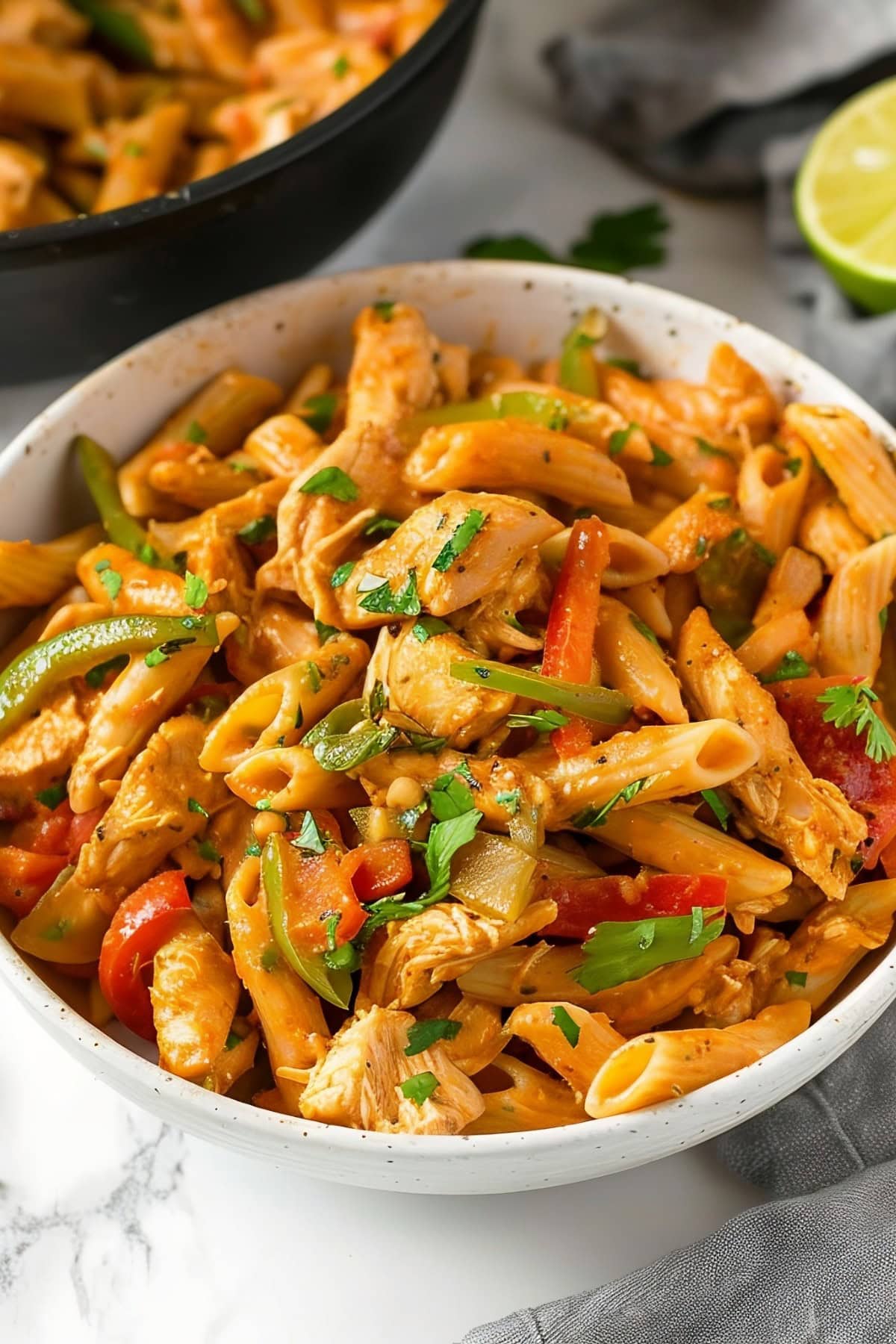 A bowl of smoky and spicy fajita-style chicken penne pasta with bell peppers and cilantro
