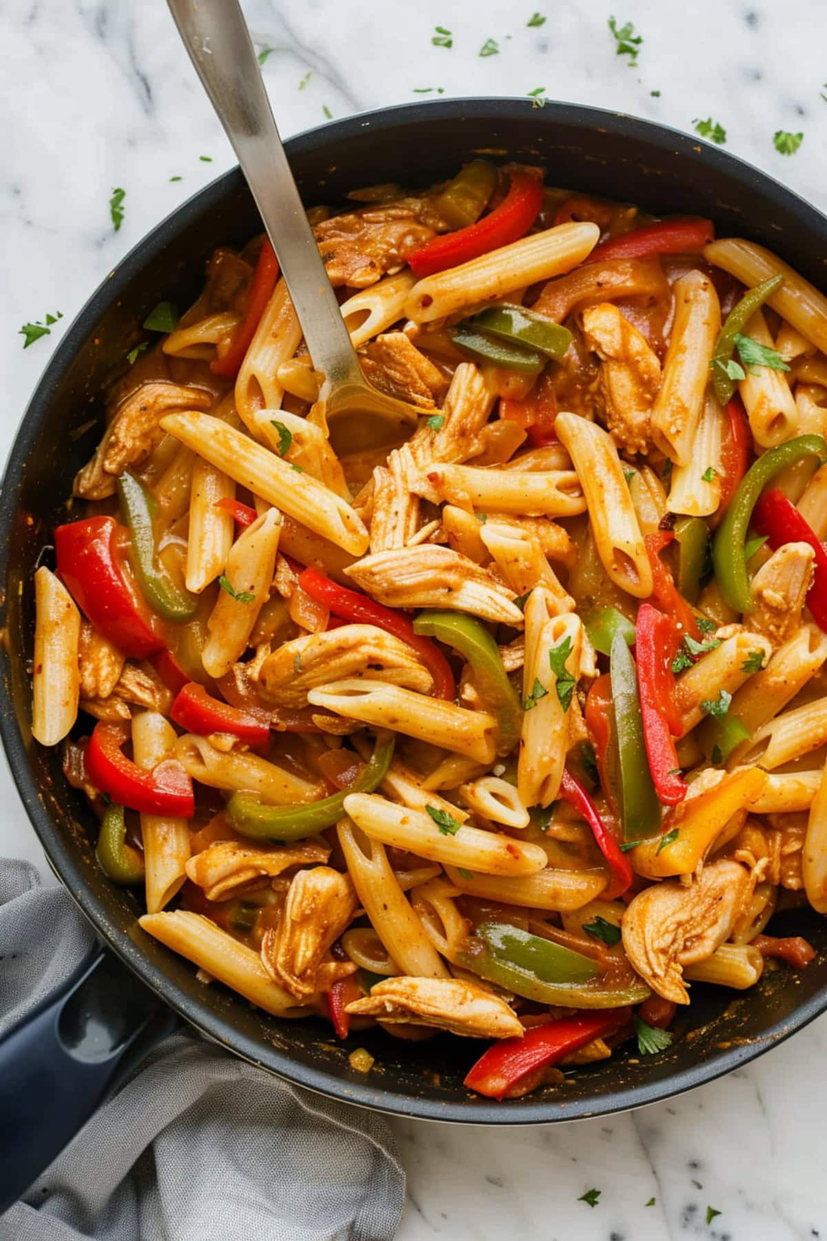 Creamy and saucy homemade chicken fajita pasta in a skillet on a white marble countertop