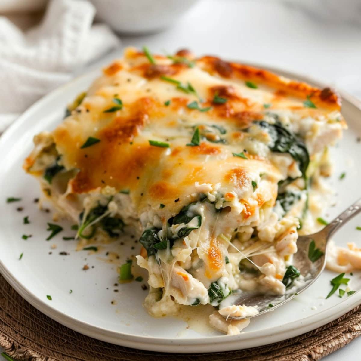 A serving of chicken and spinach casserole on a plate with spoon.
