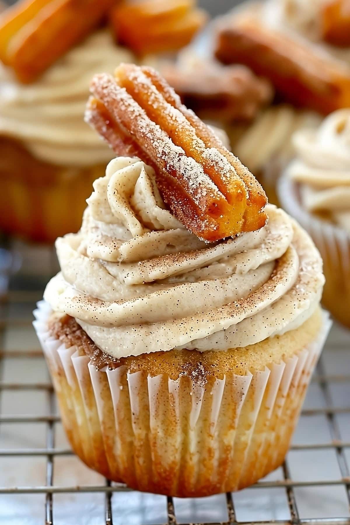 Churro cupcakes on cooling rack garnished with piece of churro.