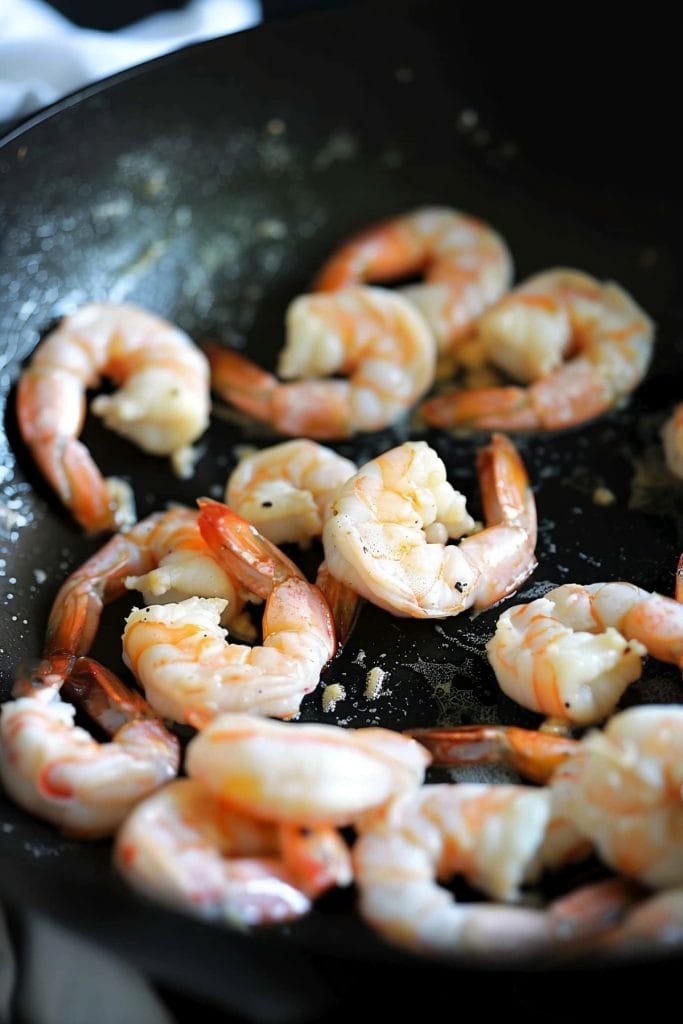 Shrimp cooking in a large skillet in a stove
