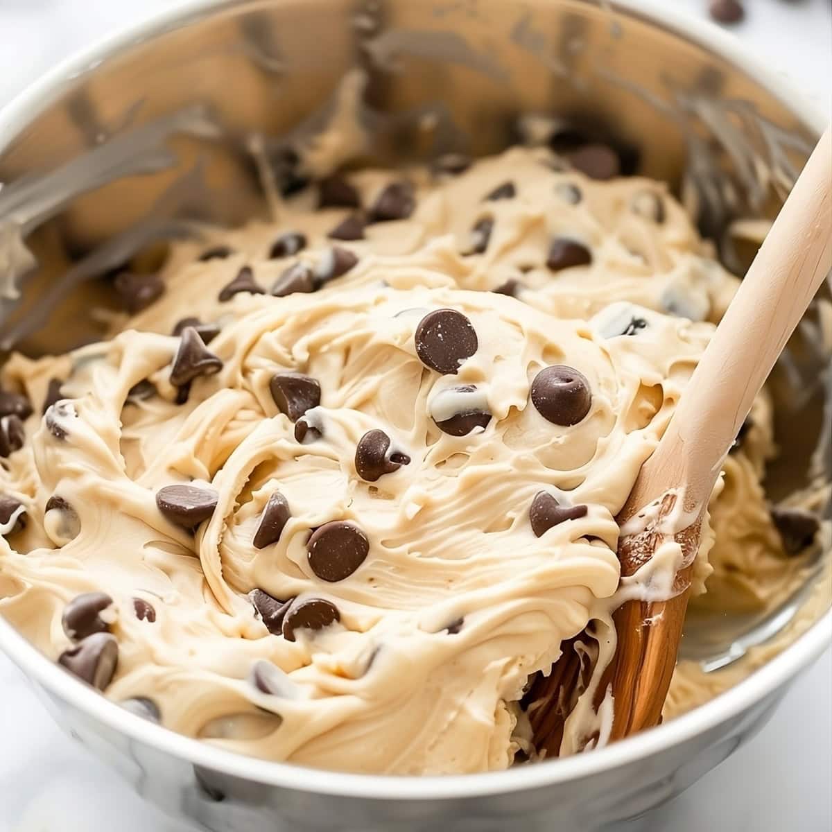 Creamy cookie dough dip with chocolate chips mixed in a mixing bowl.