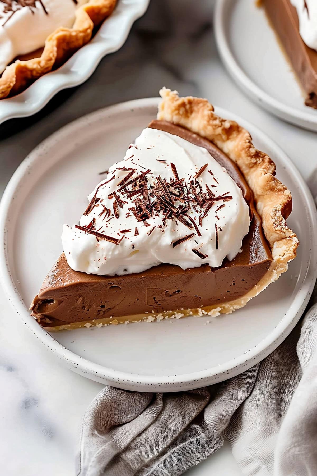 Sliced French silk pie topped with whipped cream and chocolate shavings