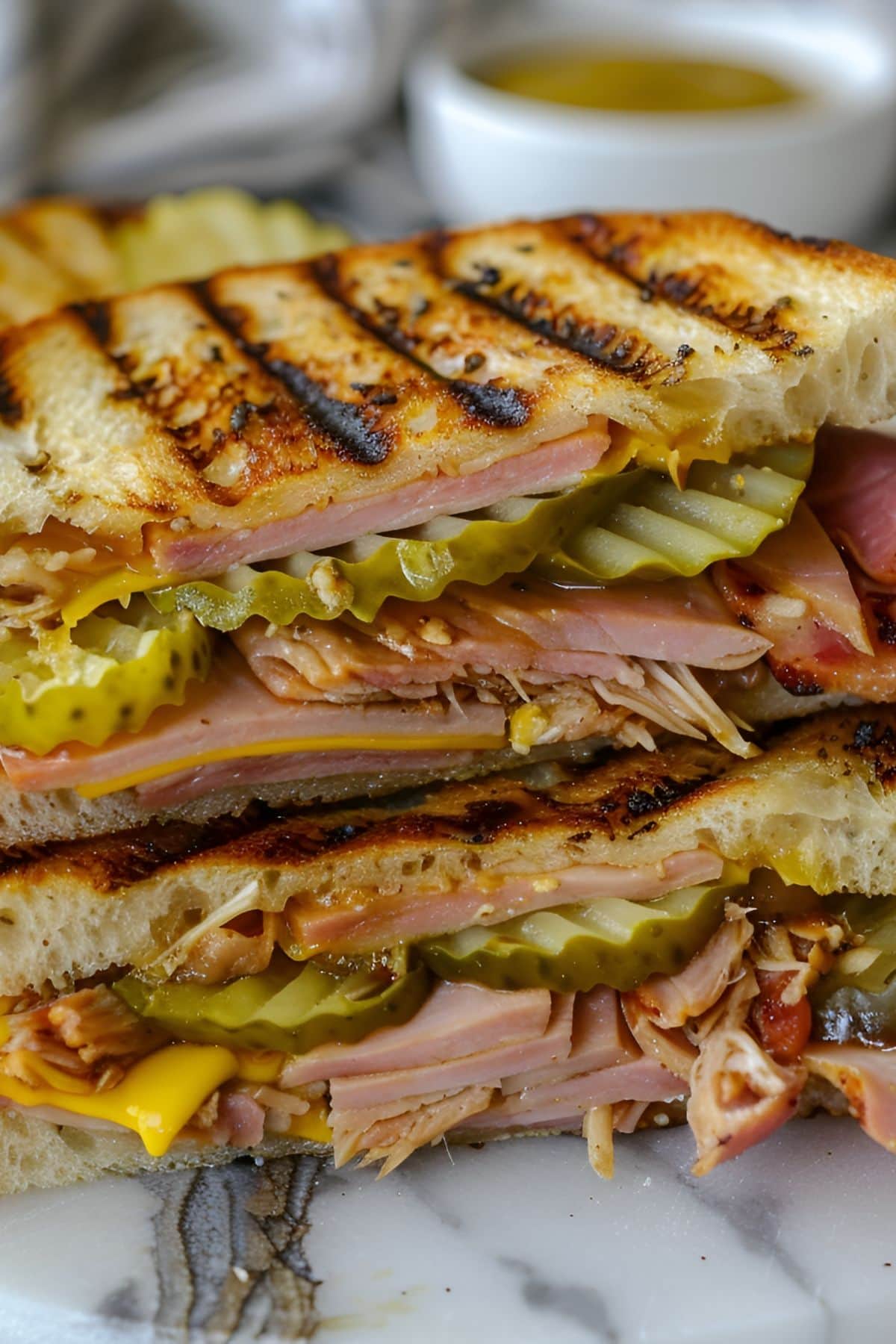 Two Halves Grilled Panini Cuban Sandwich with Ham, Pork, Cheese, Pickles, and Mustard Stacked