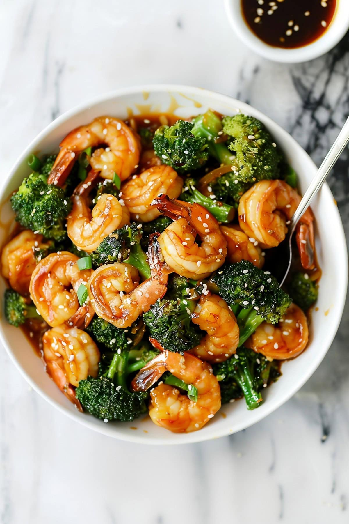 Tender and crunchy homemade shrimp and broccoli with green onions and sesame seeds, served with soy sauce