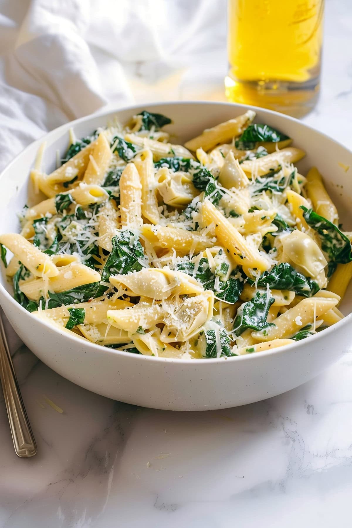 Spinach artichoke pasta in a bowl with parmesan cheese