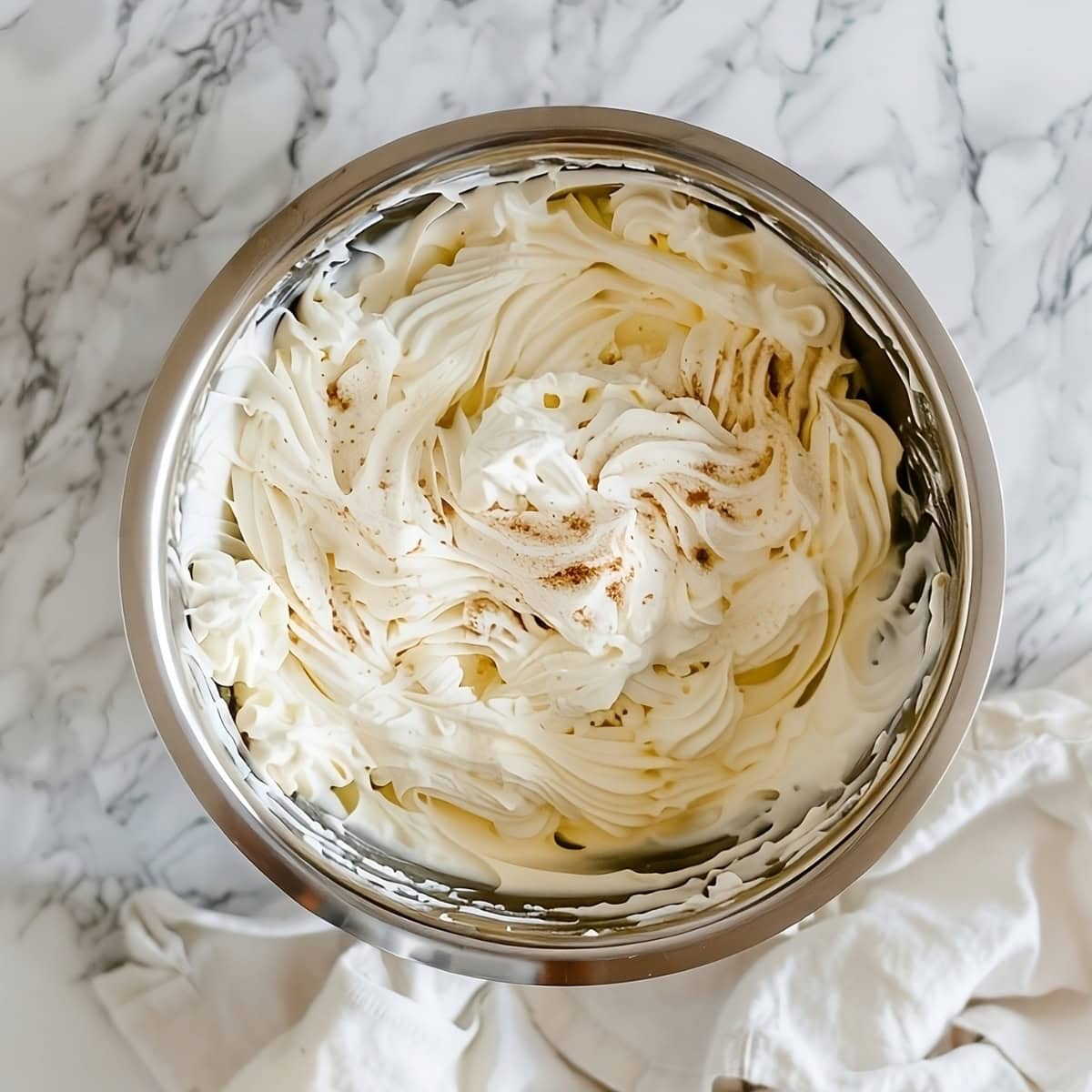 Eggnog whipped cream in a metal bowl.
