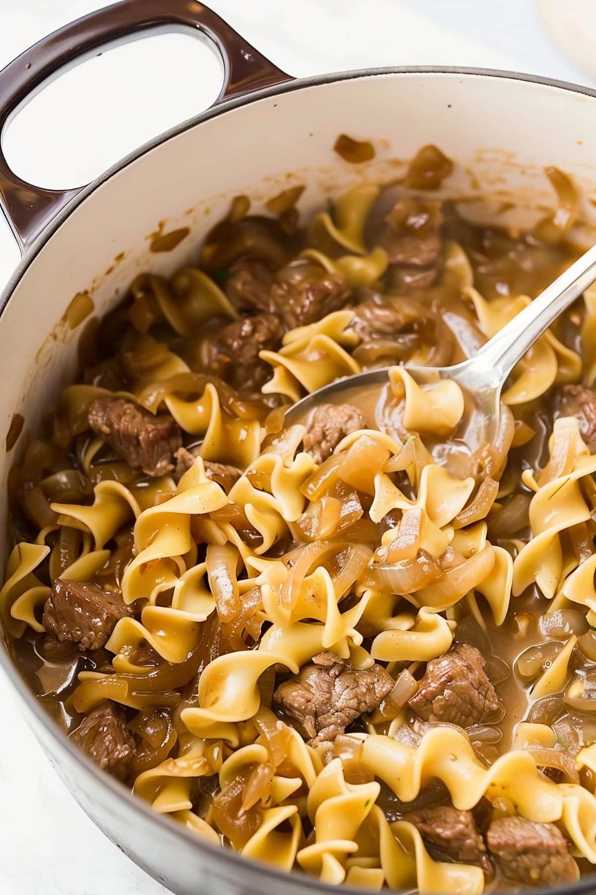 Comforting egg noodles with beef chunks and onions in a deep pot